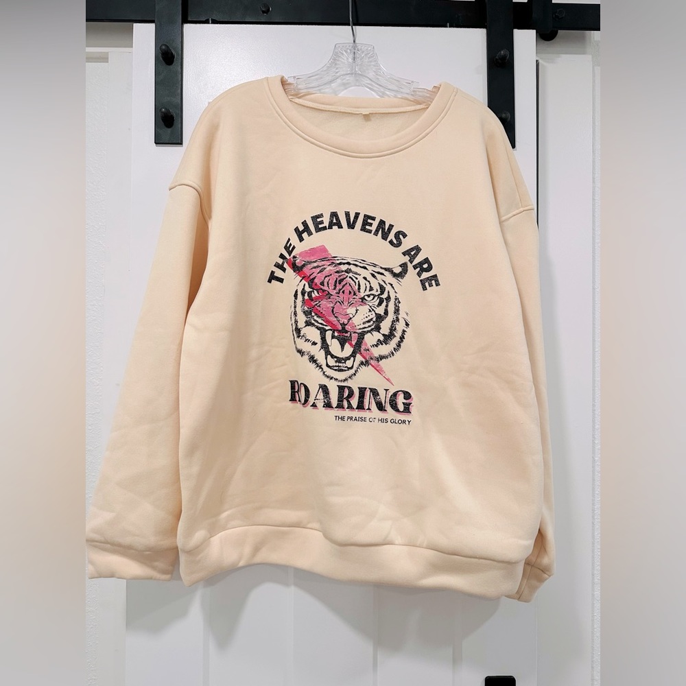 Cream “THE HEAVENS ARE ROARING” sweatshirt.